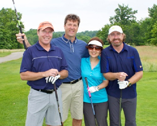 Image of four golfers, three males and one female. All of them posing for a photo.