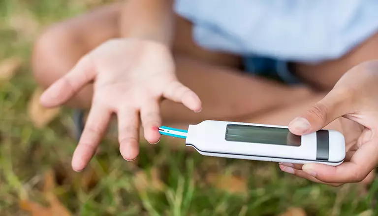 Overcoming barriers to diabetes care follow-ups | Picture of young girl testing diabetes on glucose meter - The Canadian Foundation For Pharmacy
