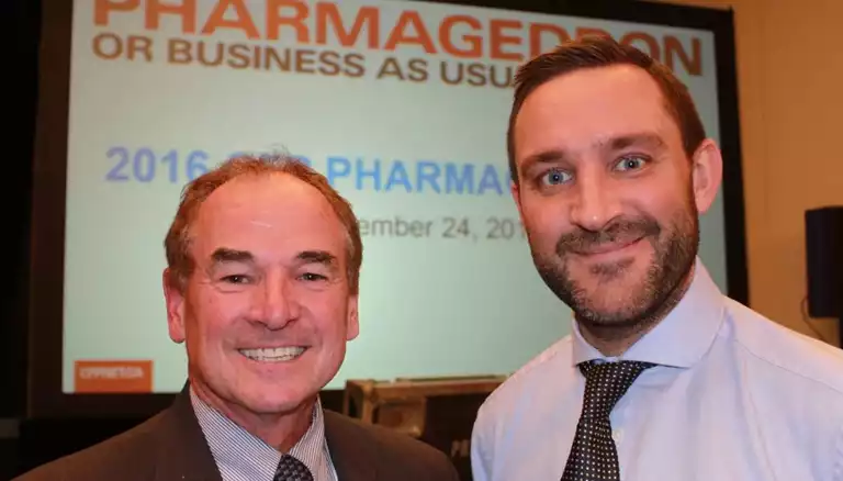 Picture of Dayle Acorn posing with Mark Burdon, with a presentation screen behind them - The Canadian Foundation For Pharmacy
