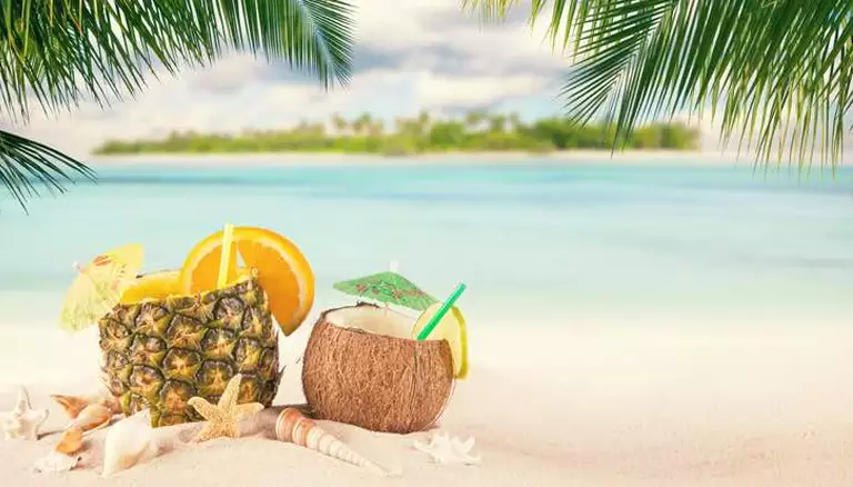 Happy, healthy travels | Picture of drink served in a coconut by the beach - The Canadian Foundation For Pharmacy