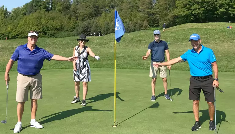 CFP's Golf Classic, from a safe distance | picture of three males and one female playing at the tournament while keeping a distance from the flag - The Canadian Foundation For Pharmacy