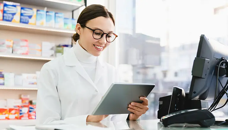 technology solutions empower pharmacists and patients | Concept photo showing a female pharmacist looking at a digital tablet by the counter - Canadian Foundation for Pharmacy