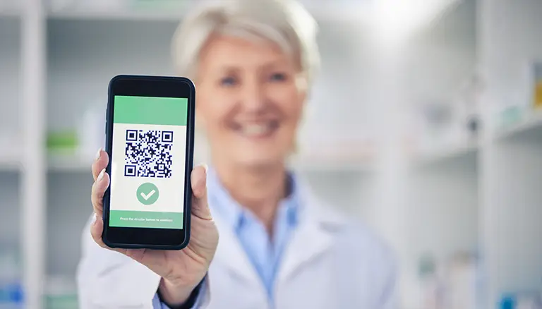 QR codes for medication education | Female pharmacist showing a QR code on a smartphone screen - Canadian Foundation for Pharmacy